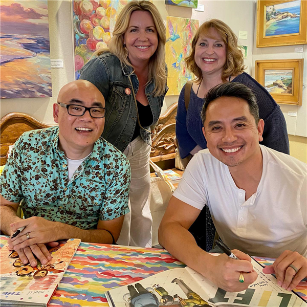 Two teachers pose with children's authors Dan Santat and Minh Le